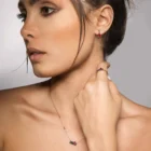 Model wearing 18kt rose gold ruby and black diamond jewelry set with necklace, earrings, and ring