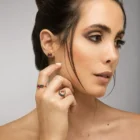 Model wearing rose gold jewelry with black diamond and ruby details, including earrings, rings, and necklace