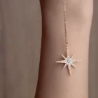 Close-up of Stella Long Pendant diamond star pendant necklace in 18kt rose gold worn on a model