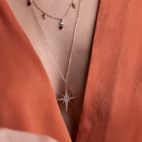 Model wearing Stella Long Pendant diamond star pendant necklace in 18kt rose gold layered with another necklace